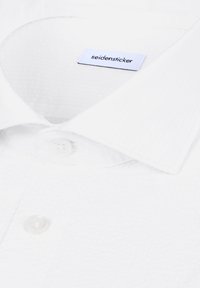 Hvid skjorte med krave og knapper samt en synlig "seidensticker" mærkeetiket inde i kraven.