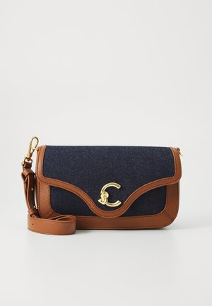 Denim and brown leather crossbody bag with a gold-tone clasp and wavy design, featuring an adjustable strap and smooth texture.