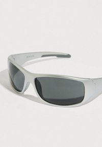 Αθλητικά γυαλιά με γκρι πλαστικό σκελετό, σκουρόχρωμους φακούς και κυρτό σχεδιασμό. Διαθέτουν διακριτικό λογότυπο στο εσωτερικό του βραχίονα.