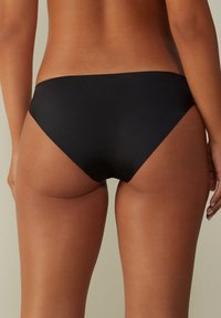 Schwarze Bikiniunterteile aus glattem, dehnbarem Stoff. Tiefer Schnitt mit minimaler Abdeckung und nahtlosen Kanten für einen sauberen Abschluss.