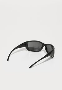 Black sunglasses with gray lenses, a sleek plastic frame, and slender arms, featuring a green accent on the left side.