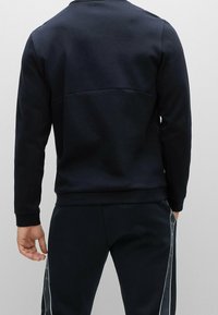 Sudadera navy con textura suave y cuello redondo. Presenta un diseño de panel trasero, puños ribeteados y una silueta ajustada.