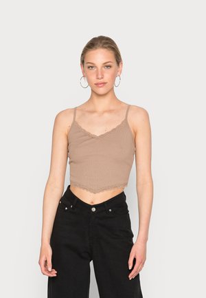 Top cropped castanho com nervuras e detalhe de renda no decote e na bainha. Alças finas ajustáveis. Usado com calças pretas de cintura alta.