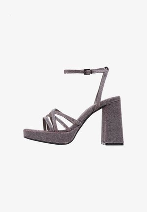 Sandalia de plataforma con tacón alto, tiras de terciopelo gris, hebilla en el tobillo y tacón ancho sobre un fondo blanco.
