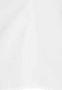 Vitt tyg med en vertikal söm som går ner längs mitten och en subtil stickad kant vid nederkanten.