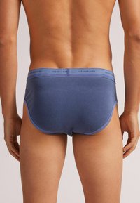 Granatowe męskie slipy o gładkiej fakturze, z miękkim pasem w talii z nadrukiem "intimissimi" w jasnoniebieskim kolorze.