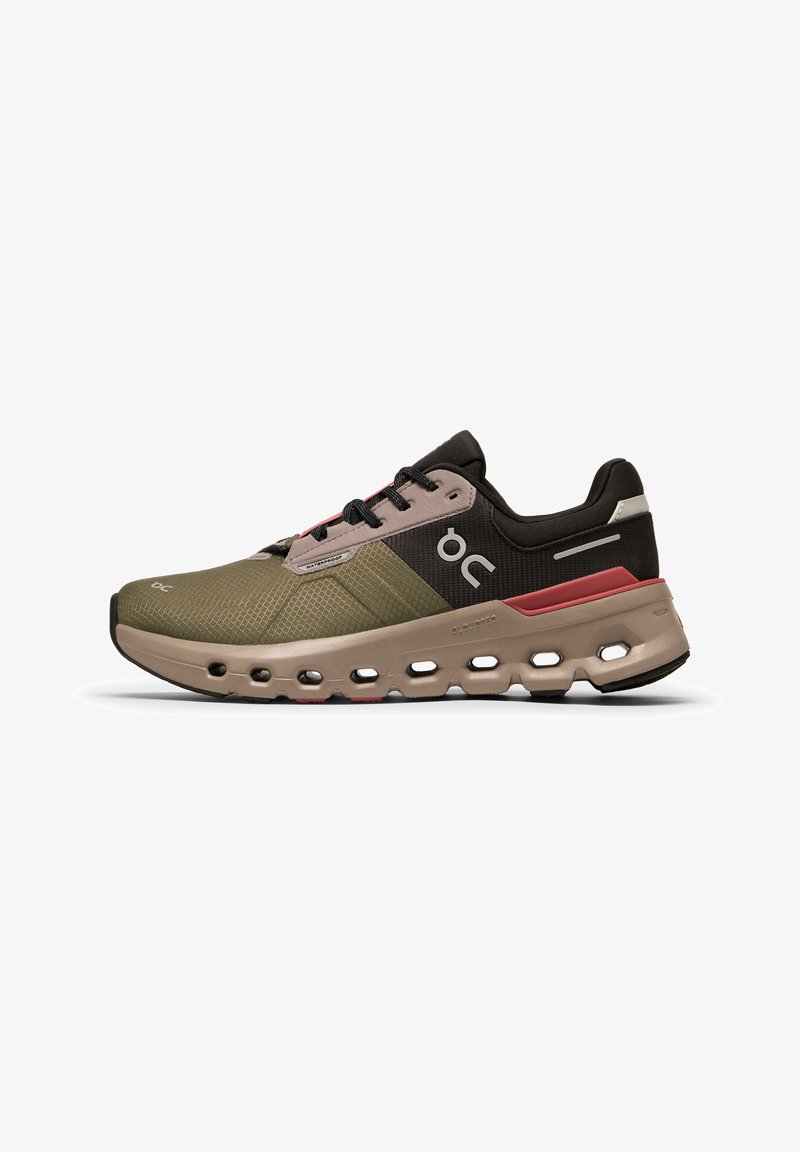 Chaussures de sport en vert foncé et noir avec une tige texturée, des accents roses et une semelle épaisse présentant des découpes pour un amorti et un soutien.