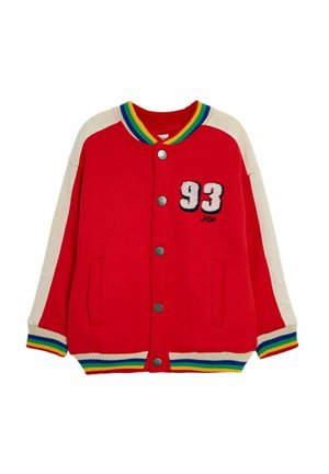Rød varsity jakke med lange cremefarvede ærmer, med en ribbet krave med regnbue-striber. Trykknapper og nummeret "93" i broderet detalje.