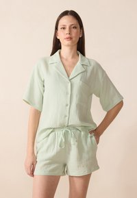 Lys grønn, teksturert loungewear-sett med en knappopp skjorte med korte ermer og shorts med snøring, med en brystlomme.