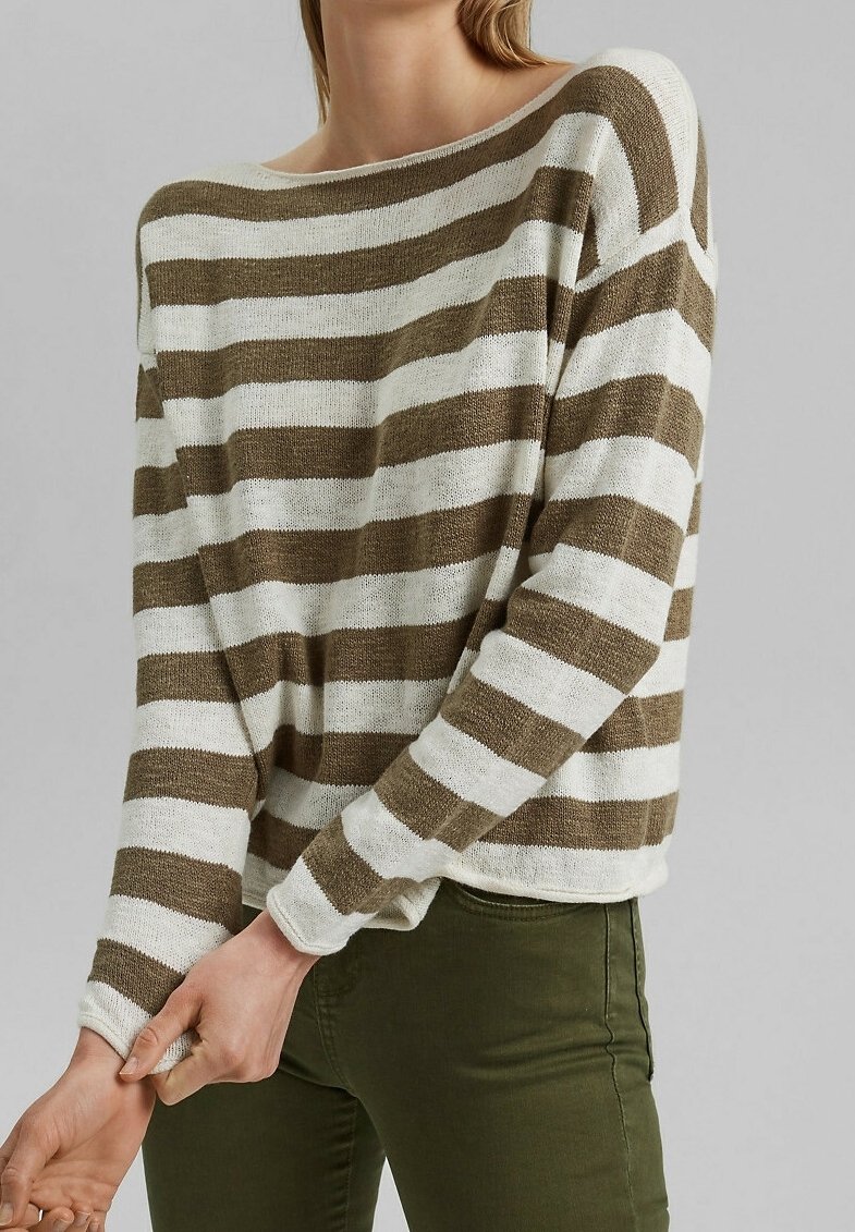 Personne portant un pull ample à manches longues avec de larges rayures horizontales blanches et vert olive et un pantalon ajusté vert olive.