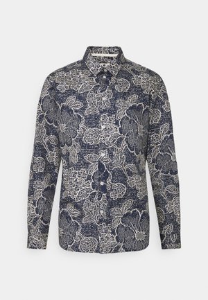 Langærmet skjorte med knapper, navyblåt og hvidt blomsterprint og spids krave på en ensartet lys baggrund.