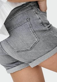 Szare dżinsowe szorty z podwiniętym dołem, z tylną kieszenią i teksturowanym wykończeniem, podkreślające klasyczny casualowy design.