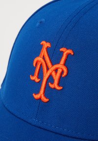 Kék baseball sapka narancssárga hímzett "NY" logóval, texturált anyagból és sima, ívelt karimával.