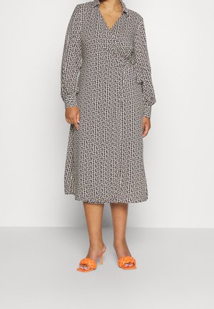 Czarno-biała sukienka na długi rękaw z kopertowym fasonem i geometrycznym wzorem, z dekoltem w serek i zwiewną spódnicą. Połączona z jasnopomarańczowymi sandałami na obcasie.