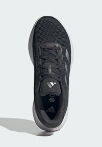 Chaussure de sport noire avec une tige en maille, dotée de lacets noirs, d'accents gris et d'une semelle blanche. L'intérieur comprend un logo et un détail texturé.