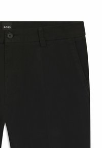 Czarne chinosy o gładkiej teksturze, z zapięciem na guzik, ukośnymi kieszeniami z przodu oraz metką z logo na pasie.