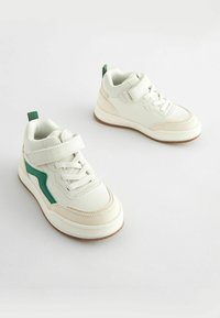 Hvide sneakers lavet af syntetisk læder med grønne accenter, rund tå, snørebåndsdesign og en velcro-lukning. Tekstureret gummisål.