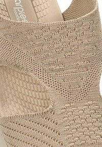 Zapato de punto beige con diseño abierto, patrones texturizados y detalles elásticos para mayor comodidad. Ligero y con suela flexible.