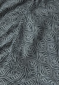 Bavlněná tkanina se vzorem listů v tmavě šedé a černé na světle šedém pozadí, s hladkou texturou a jemným leskem.