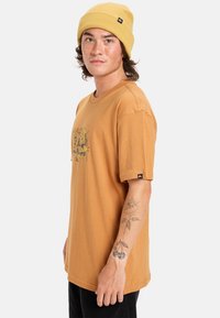 Bruine katoenen t-shirt met korte mouwen en een ronde hals, met een bedrukte graphic op de voorkant en een klein merklabel op de mouw.