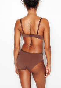 Set di lingerie marrone con tessuto morbido; il reggiseno ha spalline regolabili e chiusura a gancio, completato da slip a vita alta che si abbinano al design.