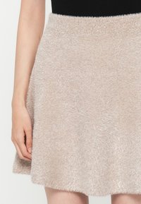 Απαλή ροζ, απαλή φούστα στο γόνατο με ελαστική μέση και μαλακή υφή. Ο σχεδιασμός διαθέτει φαρδιά γραμμή και ελάχιστες λεπτομέρειες.