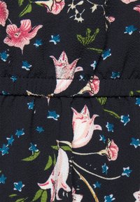 Czarna tkanina o teksturowanym wykończeniu z różowymi i niebieskimi kwiatowymi wzorami oraz zielonymi liśćmi, akcentowana małymi niebieskimi gwiazdkami.