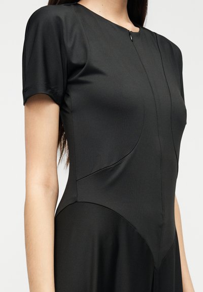 Μαύρο εφαρμοστό φόρεμα με κοντά μανίκια, με στρογγυλή λαιμόκοψη και κεντρικό φερμουάρ. Λείο, ελαφρύ ύφασμα με διακριτικές ραφές.