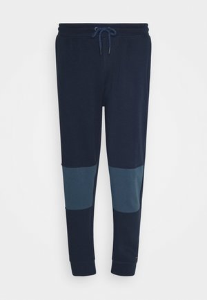 Marineblauwe joggerbroek met een tailleband met trekkoord en contrasterende donkerblauwe kniepads, elastische boorden bij de enkels.