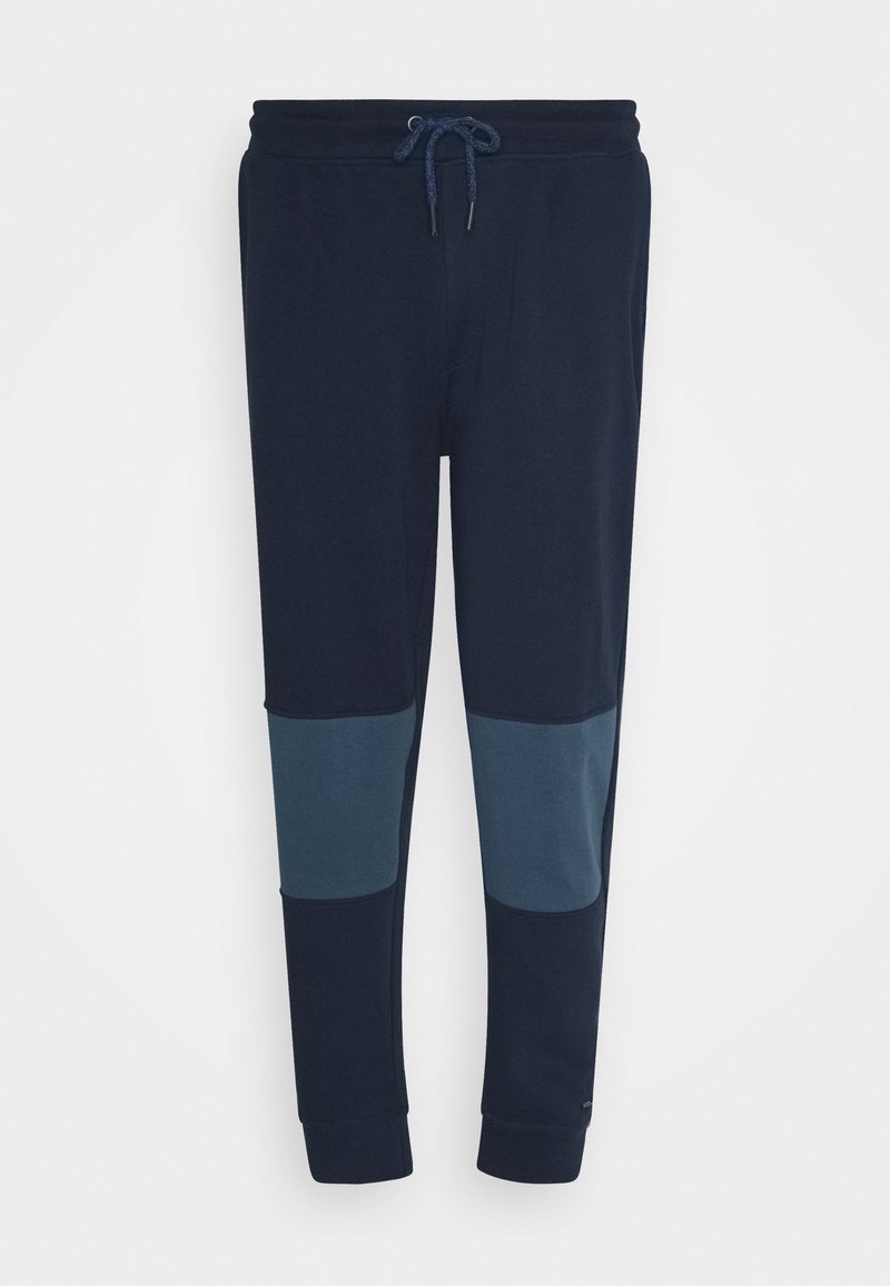 Granatowe dresowe spodnie typu jogger z ściągaczem w pasie i kontrastującymi, ciemniejszymi łatami na kolanach, elastyczne mankiety przy kostkach.