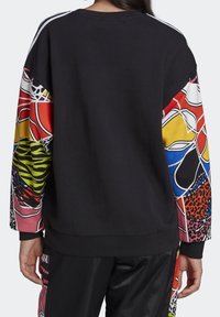 Zwarte sweatshirt met kleurrijke patroonmouwen, waaronder dierenprints en abstracte vormen. Losse pasvorm met ribgebreide manchetten.