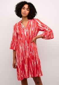 Robe à motifs rouges et blancs avec un décolleté en V, des manches cloche trois-quarts et un design à volants. Tissu léger avec une coupe fluide.