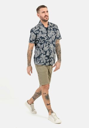 Korte mouwen marineblauw shirt met een wit bloemenpatroon, gecombineerd met beige cargoshorts en witte sneakers. Soepele stof, casual ontwerp.