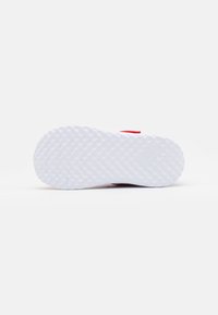Sneaker rossa con una suola in gomma bianca testurizzata. La suola presenta un motivo ondulato, che offre trazione, mentre la parte superiore è liscia ed elegante.