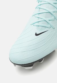 Gaiši zili futbola zābaki ar teksturētu virsmu un baltajiem akcentiem. Iezīmē melno Nike logo un auklu dizainu, demonstrējot sintētisko materiālu.