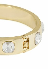 Guldarmband med fyra klara, slipade stenar inlagda i ett slätt band. Armbandet har ett gångjärnslock för enkelt användande.