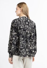 Black and white floral print blouse with long balloon sleeves, gathered detail at the back, and a rounded neckline. Lightweight fabric.
