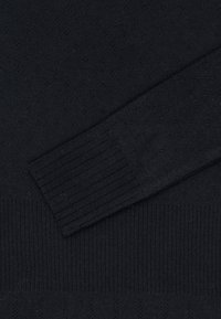 Dunkler Strickpullover mit einem strukturierten Muster aus kleinen Rautenformen; gerippte Bündchen und Saum; glattes, weiches Material.
