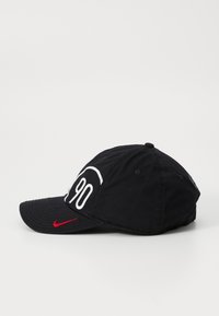 Sort baseball cap med en buet skygge, prydet med et stort hvidt "90" broderet design og et lille rødt Nike-logo på siden.