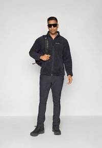 Tamsiai mėlyna fliso striukė su užtrauktuku, minkštu audiniu. Derinama su juodomis lengvomis kelnėmis ir tvirtais juodais batais. Kuprinė su dirželiu.