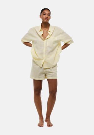Chemise à manches courtes rayée jaune et blanche avec poche et shorts assortis, fabriqués en tissu doux, présentant une coupe décontractée et un col.
