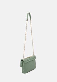 Bolso cruzado de imitación cuero verde con un diseño acolchado, correa de cadena dorada y solapa plegable. Textura suave, forma rectangular compacta.