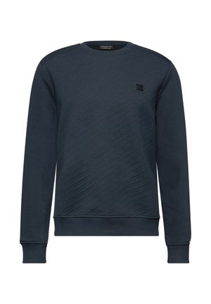 Tummansininen collegepaita, joka on valmistettu teksturoidusta kankaasta. Paidassa on vinoviivat, pyöreä pääntie ja pieni logopatch rintataskussa.