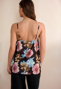 Zwarte bloemen camisole met dunne bandjes, versierd met grote roze en blauwe bloemen. Vloeiend stof met een gladde textuur, rugloos ontwerp.
