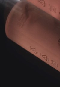 Przezroczysta butelka z różowym płynem, wygrawerowane symbole na powierzchni, gładka tekstura, nowoczesny design i współczesna estetyka.