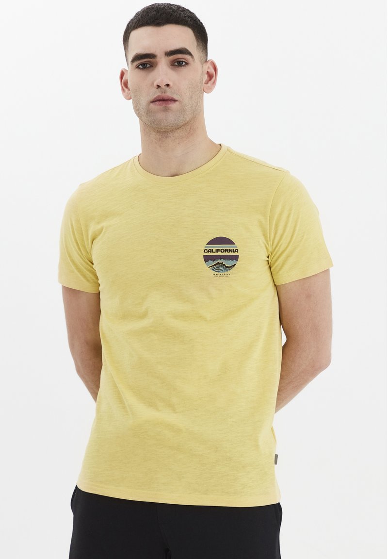 Gul bomulds t-shirt med korte ærmer og rund hals. Har et trykt rundt logo med "CALIFORNIA" og bjergdesign på brystet.