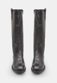 Fekete bőr, térd fölé érő csizmák sima textúrával, lekerekített orral és oldalsó cipzárral. Tiszta vonalakkal és minimális részletezéssel rendelkezik.