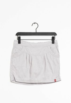 Jupe grise claire au design plissé, avec des poches latérales et une taille. Le tissu semble lisse avec une texture subtile. Suspendue à un cintre noir à clip.