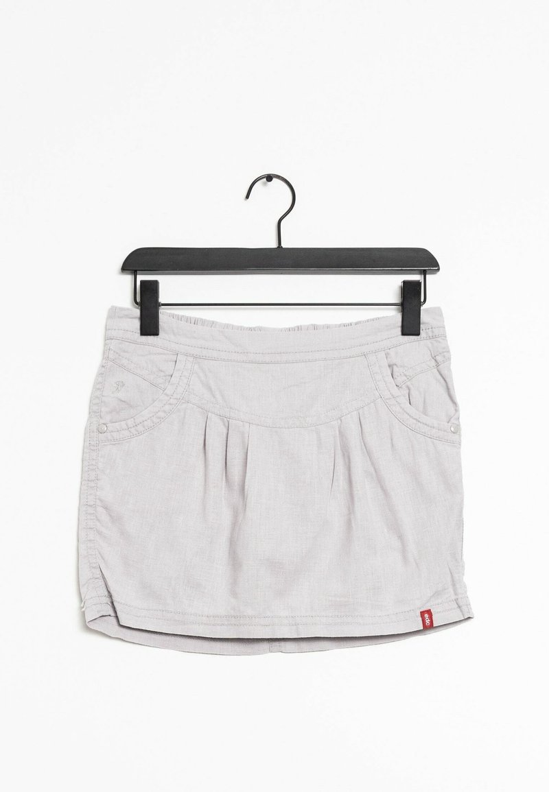 Hame vaale har maela, jo pleated design, side pockets, aur ek waistband ke saath hai. Kapda smooth dikhta hai, jismein halka sa texture hai. Yeh ek kale clip hanger par latak raha hai.