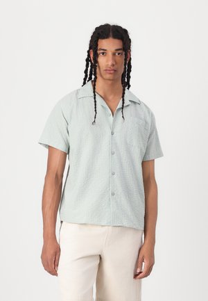 Short-sleeve, light green button-up shirt with a textured pattern and a chest pocket, made of a soft fabric, featuring a classic collar.